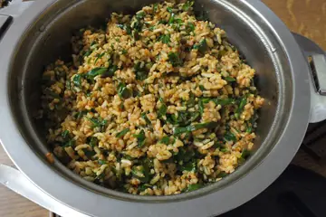 Rice cooked with green leaves and spice in a steel pot