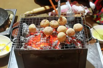 Tapte hue koyle par taar ki jaali par seke jaa rahe gol litti ke goondh, ek cook unhe palatta hua