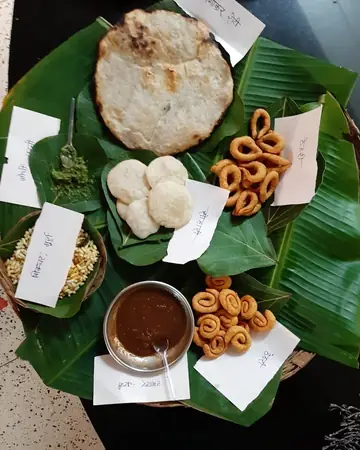 Ring-shaped and round Chhattisgarhi snacks, a rice-flour roti and chutney arranged on banana leaves in a basket