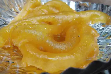 A hot orange jalebi on a foil-lined plate at Chandni Chowk