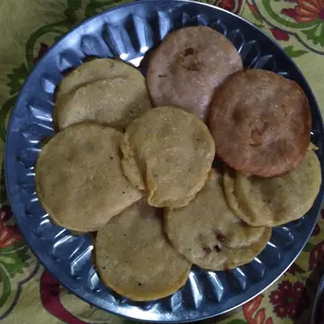 A steel plate of round fried dhuska made of rice and urad dal