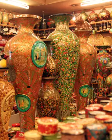 Tall painted papier-mâché vases and stacked boxes on the shelves of a handicraft shop
