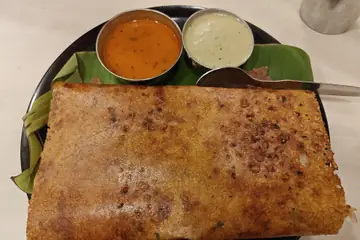A crisp rava onion masala dosa on a banana leaf with chutney and sambar at Wilson Garden, Bangalore