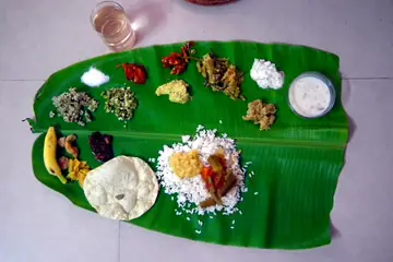 An Onam sadya meal laid out on a banana leaf: rice, a papadam, a banana and small portions of curries