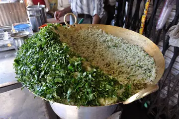 Vidisha mein sadak ke thele par chaudi peetal ki kadhai mein poha ka dher, bagal mein kati hui hari dhaniya
