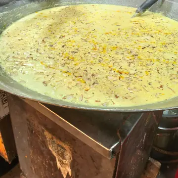 A wide pan of thick yellow rabdi with nuts and saffron at a street stall in Indore