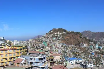 Coloured houses and shops covering a hill in Aizawl under a blue sky