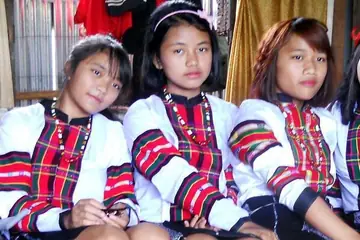 Young women in white tops with red-checked Mizo patterns, seated side by side