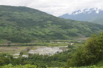 A green hill valley with terraced paddy fields at the bottom and cloud over the far ridge, near Kohima, Nagaland