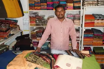 A shopkeeper behind a counter of folded Sambalpuri sarees at Ekamra Haat, Bhubaneswar