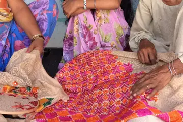 Women stitching a bright pink and orange phulkari cloth by hand in Rajpura