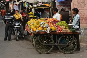 A wooden fruit cart piled with papaya, apples, grapes and bananas in a market lane in Pushkar