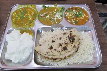 A steel thali with three dals, rice, curd and a roti, served in Jaipur