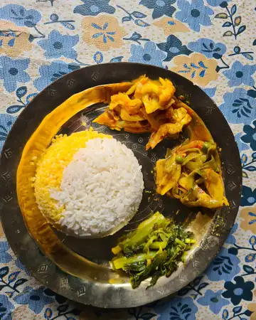 A steel plate of rice, dal and vegetable curries on a flowered cloth