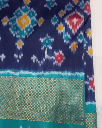 Blue ikat cloth with red, yellow and teal diamond patterns and a green zari border
