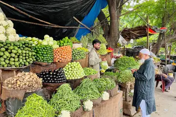 డెనిమ్ చొక్కా వేసుకున్న ఒక వ్యక్తి బయట కూర్చుని చేతిలోని ఫోన్ వైపు చూస్తున్నాడు