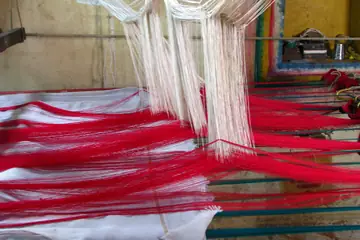 Red and white silk threads stretched on a handloom for a sari in Kanchipuram