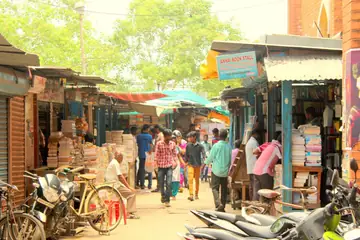 A lane of old-book stalls with shoppers walking between them at Moore Market, Chennai
