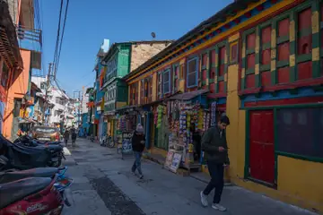 A bazaar street in Almora with painted wooden shopfronts and goods hung outside the shops