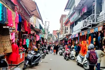 A market lane of clothes stalls hung with salwar suits and lehengas, shoppers and scooters on the road
