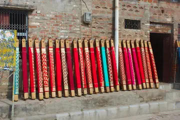 Red and gold Banarasi saris standing on wooden blocks outside a shop in Varanasi