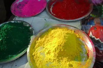 Brass plates heaped with pink, red, green and yellow Holi gulal