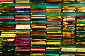 Shelves of brightly coloured folded saris stacked in neat rows