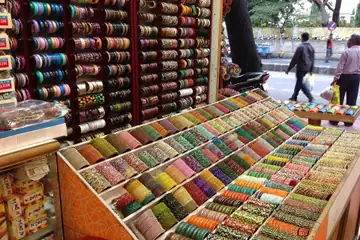A slanted glass counter of colourful bangles sorted by colour in a roadside bangle store in Mysuru, Karnataka