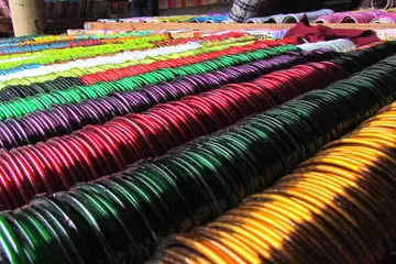മഹാരാഷ്ട്രയിലെ പൂണെയിലെ ഒരു ചന്തയിലെ സ്റ്റാളിൽ പച്ച, പിങ്ക്, കറുപ്പ്, സ്വർണ നിറങ്ങളിലുള്ള തിളങ്ങുന്ന ഗ്ലാസ് വളകളുടെ നിരകൾ
