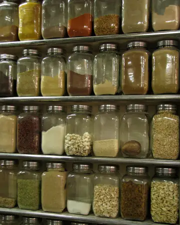 Rows of glass jars filled with spices and pulses on shop shelves