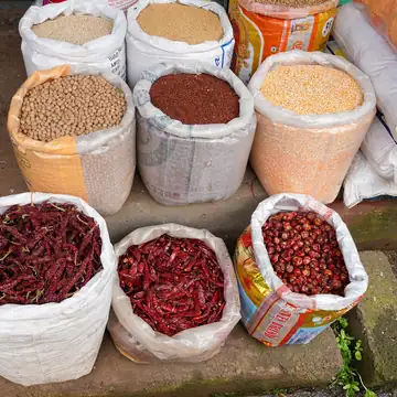 Open sacks of pulses and red chillies at a market stall