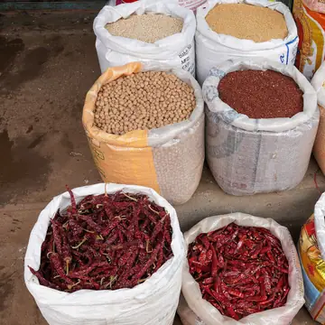 Open sacks of pulses, flour and dried red chillies lined up at a market shop
