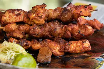 Grilled chicken tikka skewers served with a lime wedge