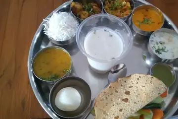 A Marwadi thali on a steel plate with dal, rice, papad and a glass of buttermilk, photographed in Delhi