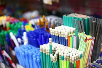 Pens, pencils and erasers stacked in bright rows at a stationery counter