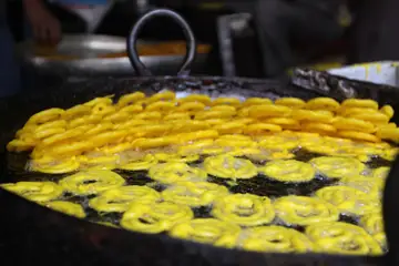 महाराष्ट्रातील नाशिकमध्ये हलवाईच्या ठेल्यावर मोठ्या कढईत तळल्या जाणाऱ्या चमकदार पिवळ्या जलेबी