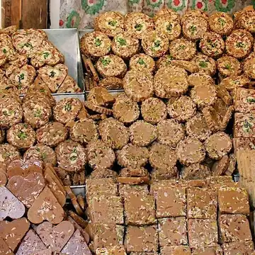 Heaped trays of nut chikki, barfi squares and sweets piled at a sweet stall in Rajasthan