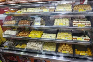 Glass shelves of packed barfi and laddus with price tags in a sweet shop