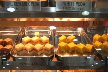 Trays of peda and burfi in a glass counter, each with its price per kilo