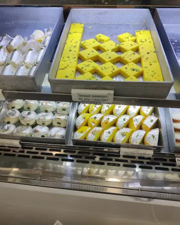 Trays of yellow diamond-cut sandesh and white sweets in a shop display