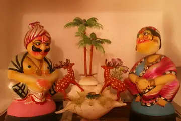 A pair of painted wooden toy figures, a man in a turban and a woman, with toy deer and palm trees