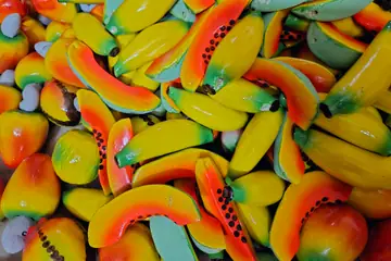 A pile of painted wooden toy bananas, mangoes and papayas