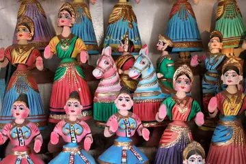 Rows of painted tilting dolls in bright dresses on shop shelves