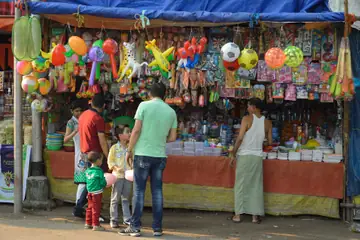 A toy stall hung with balloons, balls and toys, with a father and two small children choosing at the counter